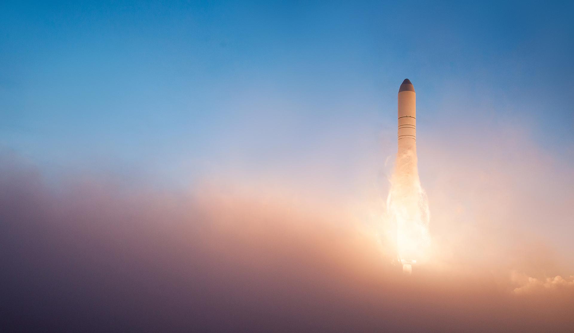 A rocket ascending into a golden-hour sky, trailing fire and smoke